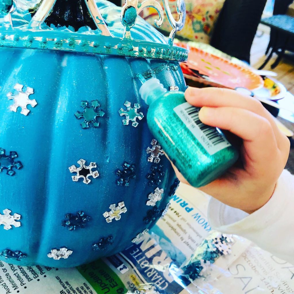 Adding a touch of glitter glue to the pumpkin