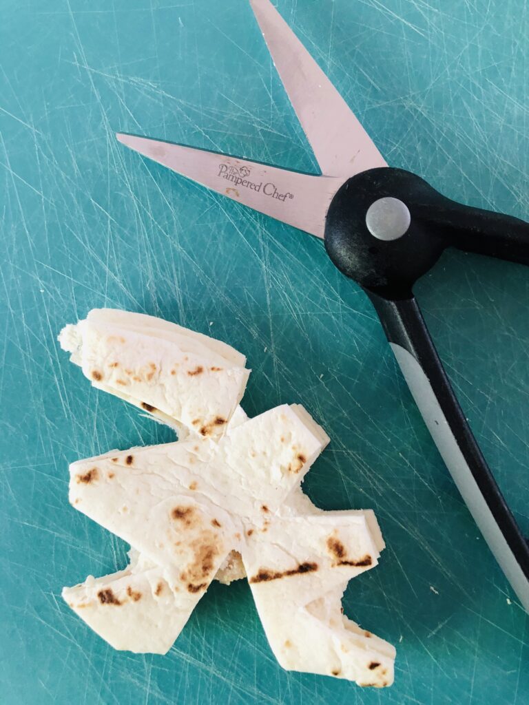 Cutting shapes into tortilla to create a snowflake pattern